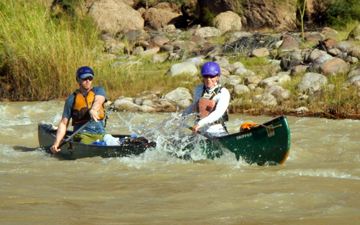 two people navigate choppy waters in a canoe